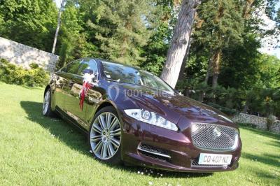 Salle de bain avec une cabine de douche moderne, un banc en bois intégré, deux vasques noires et une fenêtre avec stores.