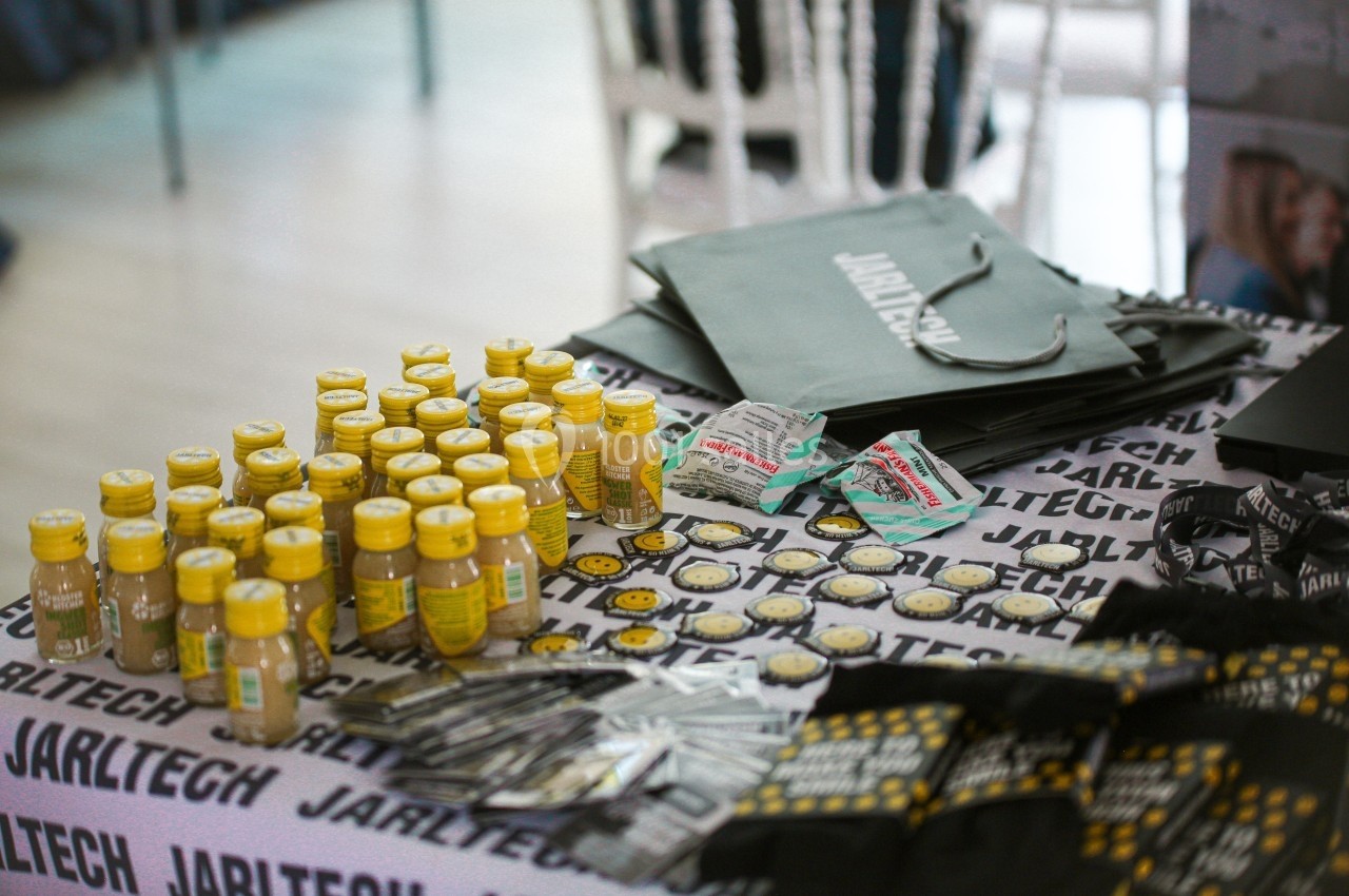 Des échantillons de boissons, badges et sacs promotionnels disposés sur une table lors d'un événement.
