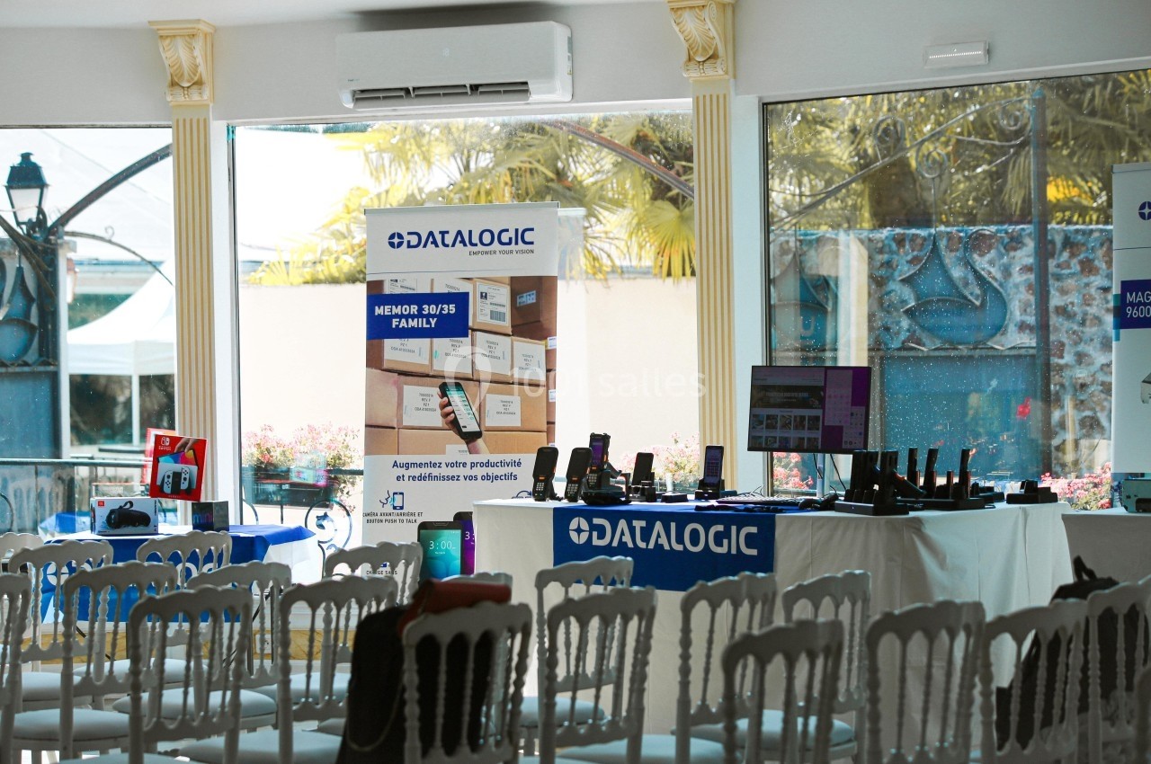 Salle de conférence avec des stands présentant des produits technologiques et des affiches de la marque Datalogic.