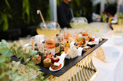 Plateau de verrines et bouchées variées disposées sur une table lors d'un événement en extérieur.