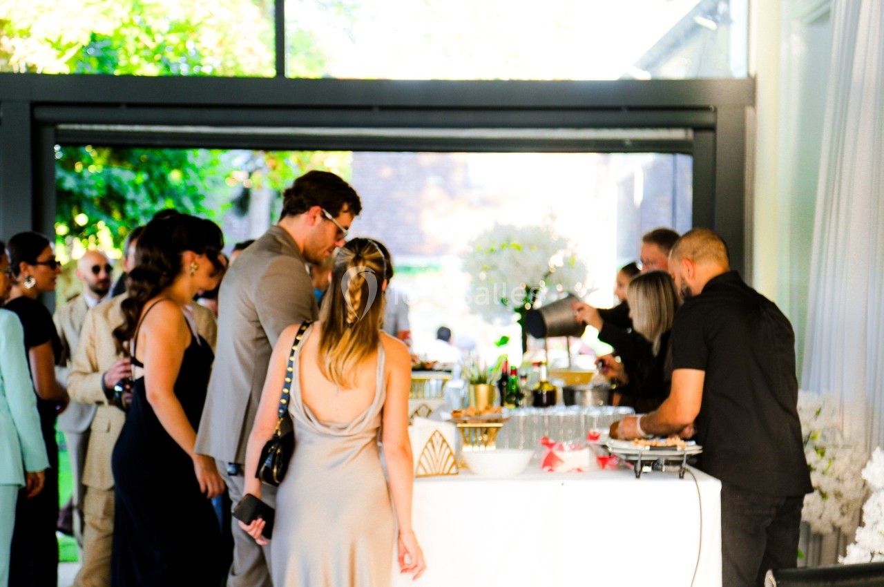 Des personnes rassemblées autour d'un bar lors d'un événement en extérieur, avec un barman servant des boissons.