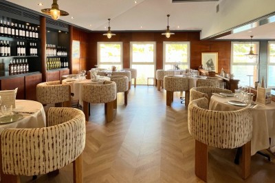 Un couple en tenue élégante regarde la mer au coucher du soleil, avec un bateau visible à l'horizon.