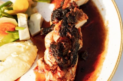 Un couple en tenue élégante regarde la mer au coucher du soleil, avec un bateau visible à l'horizon.