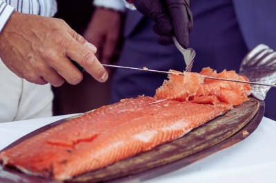 Un couple en tenue élégante regarde la mer au coucher du soleil, avec un bateau visible à l'horizon.