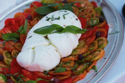 Un couple en tenue élégante regarde la mer au coucher du soleil, avec un bateau visible à l'horizon.