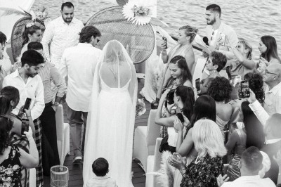 Un couple en tenue élégante regarde la mer au coucher du soleil, avec un bateau visible à l'horizon.