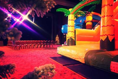 Salle lumineuse avec tables et chaises modernes, sol en moquette, cloison en bois et tapis rouge au centre.