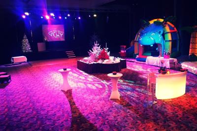 Salle lumineuse avec tables et chaises modernes, sol en moquette, cloison en bois et tapis rouge au centre.