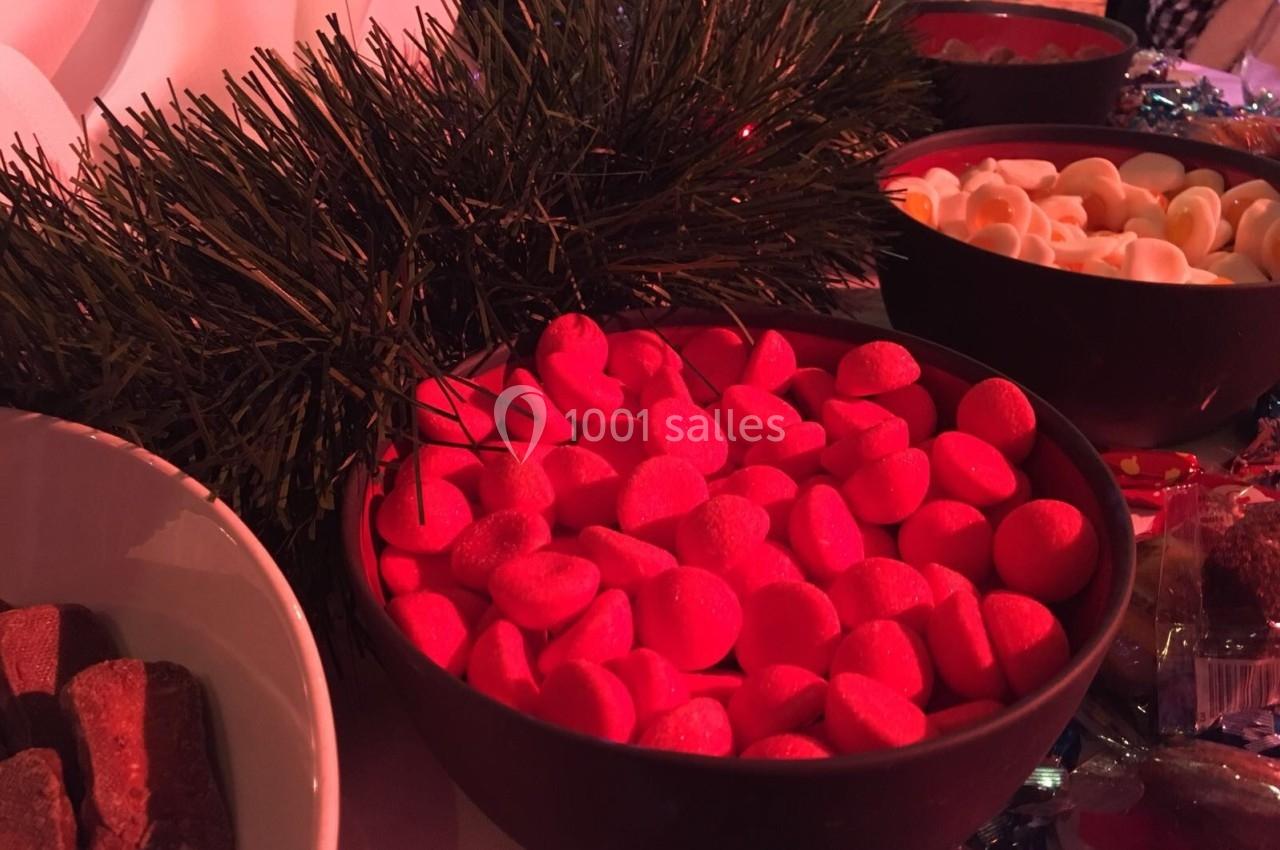 Bol de bonbons rouges entouré de décorations de Noël et d'autres bols de friandises.