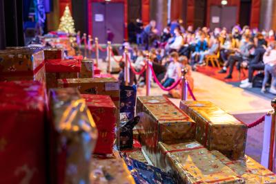 Salle lumineuse avec tables et chaises modernes, sol en moquette, cloison en bois et tapis rouge au centre.