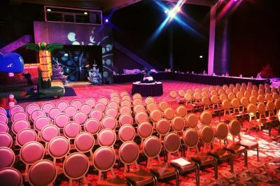 Salle lumineuse avec tables et chaises modernes, sol en moquette, cloison en bois et tapis rouge au centre.