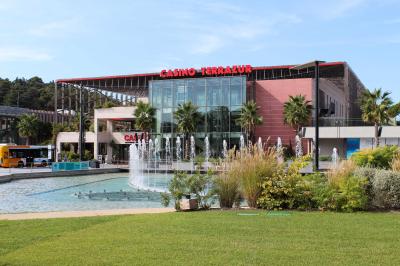 Salle lumineuse avec tables et chaises modernes, sol en moquette, cloison en bois et tapis rouge au centre.