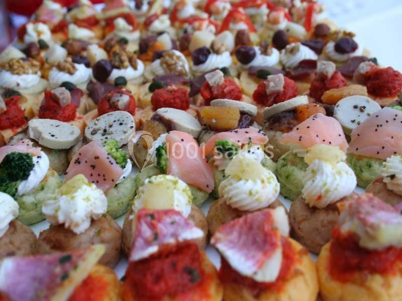 Plateau de canapés variés garnis de légumes, fromages, charcuteries et noix, disposés en rangées colorées.