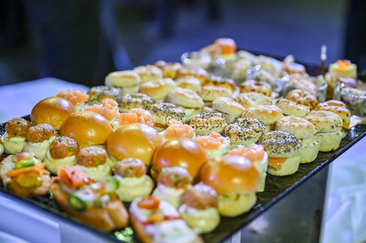 Plateau de petits pains et amuse-bouches variés garnis de saumon, fromage et autres ingrédients, présenté sur une table.