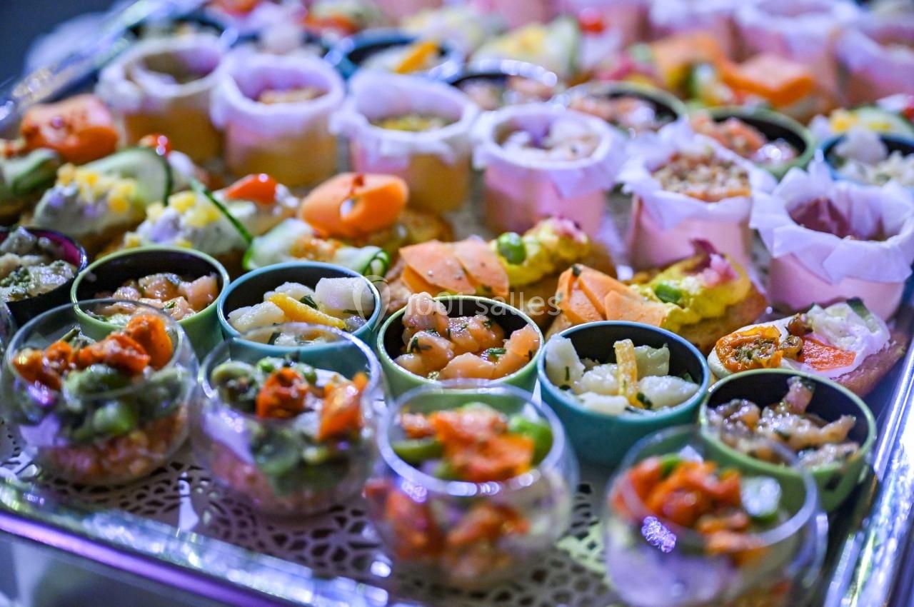 Plateau de verrines et bouchées variées, colorées et garnies d'ingrédients frais, présenté pour un buffet.