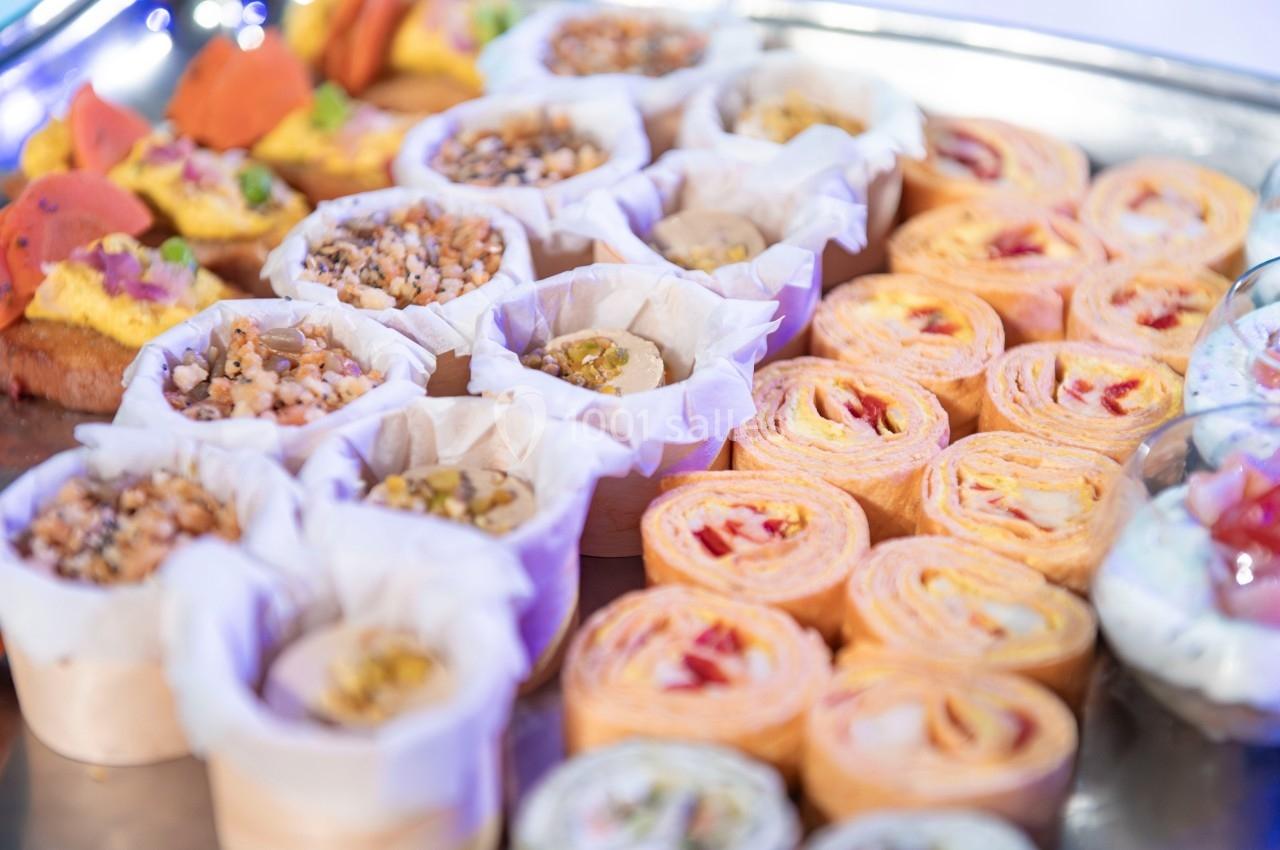 Plateau de bouchées apéritives variées, incluant des wraps roulés et des amuse-bouches garnis.