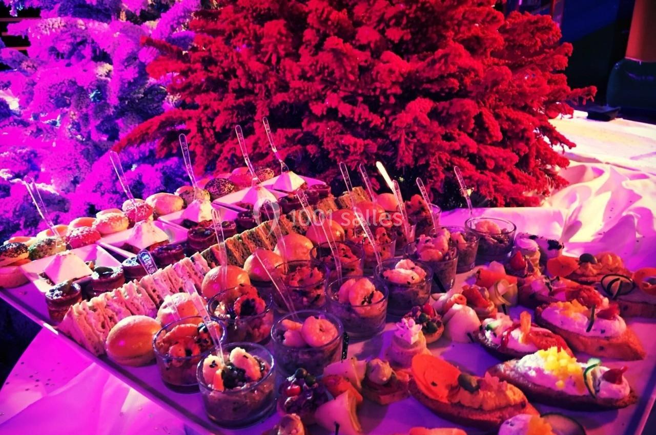 Plateau de bouchées apéritives variées devant un sapin rouge illuminé dans une ambiance festive.