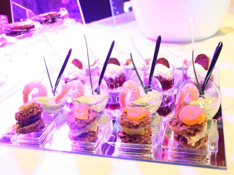 Assortiment de verrines et bouchées salées présentées sur un plateau, décorées de crevettes et légumes.