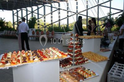 Salle lumineuse avec tables et chaises modernes, sol en moquette, cloison en bois et tapis rouge au centre.