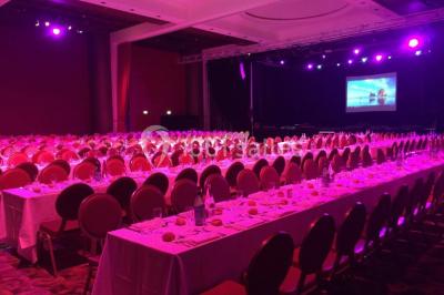 Salle lumineuse avec tables et chaises modernes, sol en moquette, cloison en bois et tapis rouge au centre.