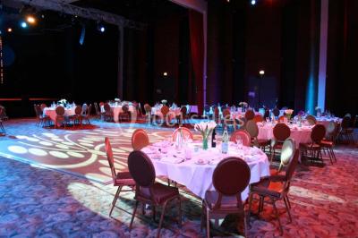 Salle lumineuse avec tables et chaises modernes, sol en moquette, cloison en bois et tapis rouge au centre.