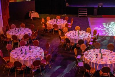 Salle lumineuse avec tables et chaises modernes, sol en moquette, cloison en bois et tapis rouge au centre.
