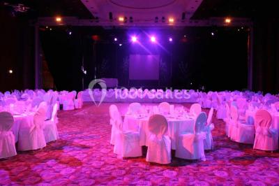 Salle lumineuse avec tables et chaises modernes, sol en moquette, cloison en bois et tapis rouge au centre.