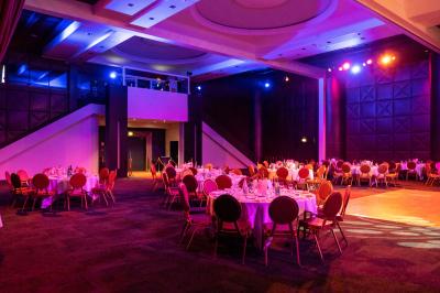 Salle lumineuse avec tables et chaises modernes, sol en moquette, cloison en bois et tapis rouge au centre.