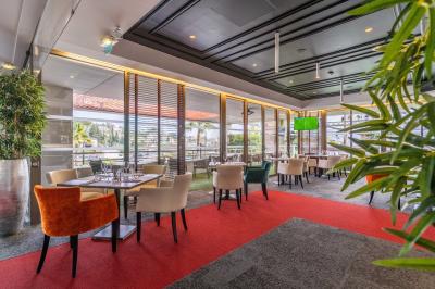 Salle lumineuse avec tables et chaises modernes, sol en moquette, cloison en bois et tapis rouge au centre.