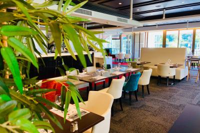 Salle lumineuse avec tables et chaises modernes, sol en moquette, cloison en bois et tapis rouge au centre.