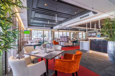 Salle lumineuse avec tables et chaises modernes, sol en moquette, cloison en bois et tapis rouge au centre.