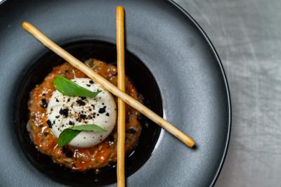 Salle lumineuse avec tables et chaises modernes, sol en moquette, cloison en bois et tapis rouge au centre.
