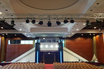 Salle lumineuse avec tables et chaises modernes, sol en moquette, cloison en bois et tapis rouge au centre.