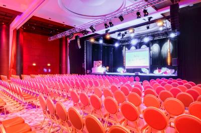 Salle lumineuse avec tables et chaises modernes, sol en moquette, cloison en bois et tapis rouge au centre.