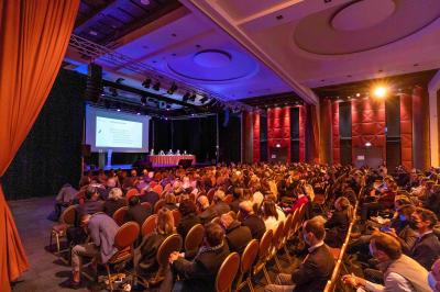 Salle lumineuse avec tables et chaises modernes, sol en moquette, cloison en bois et tapis rouge au centre.