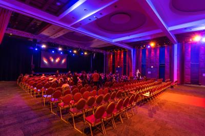 Salle lumineuse avec tables et chaises modernes, sol en moquette, cloison en bois et tapis rouge au centre.