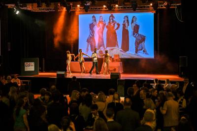 Salle lumineuse avec tables et chaises modernes, sol en moquette, cloison en bois et tapis rouge au centre.