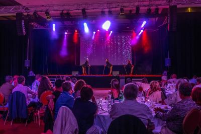 Salle lumineuse avec tables et chaises modernes, sol en moquette, cloison en bois et tapis rouge au centre.