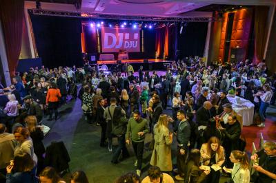 Salle lumineuse avec tables et chaises modernes, sol en moquette, cloison en bois et tapis rouge au centre.