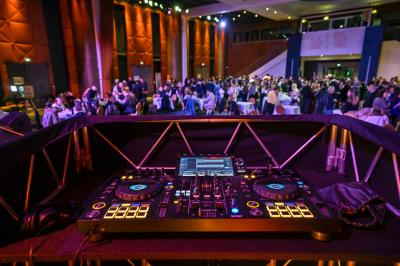 Salle lumineuse avec tables et chaises modernes, sol en moquette, cloison en bois et tapis rouge au centre.