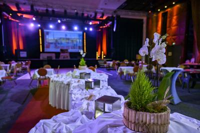 Salle lumineuse avec tables et chaises modernes, sol en moquette, cloison en bois et tapis rouge au centre.