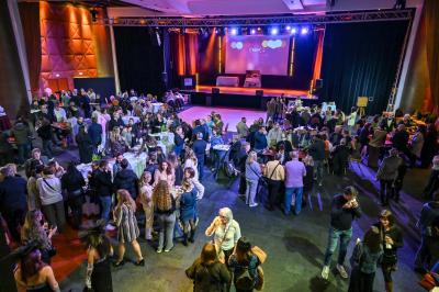 Salle lumineuse avec tables et chaises modernes, sol en moquette, cloison en bois et tapis rouge au centre.