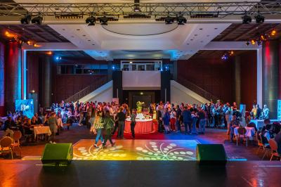 Salle lumineuse avec tables et chaises modernes, sol en moquette, cloison en bois et tapis rouge au centre.