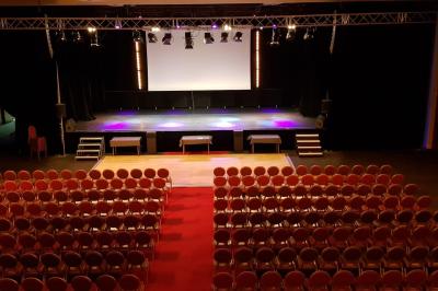 Salle lumineuse avec tables et chaises modernes, sol en moquette, cloison en bois et tapis rouge au centre.