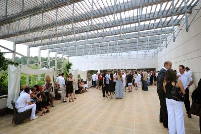 Salle lumineuse avec tables et chaises modernes, sol en moquette, cloison en bois et tapis rouge au centre.
