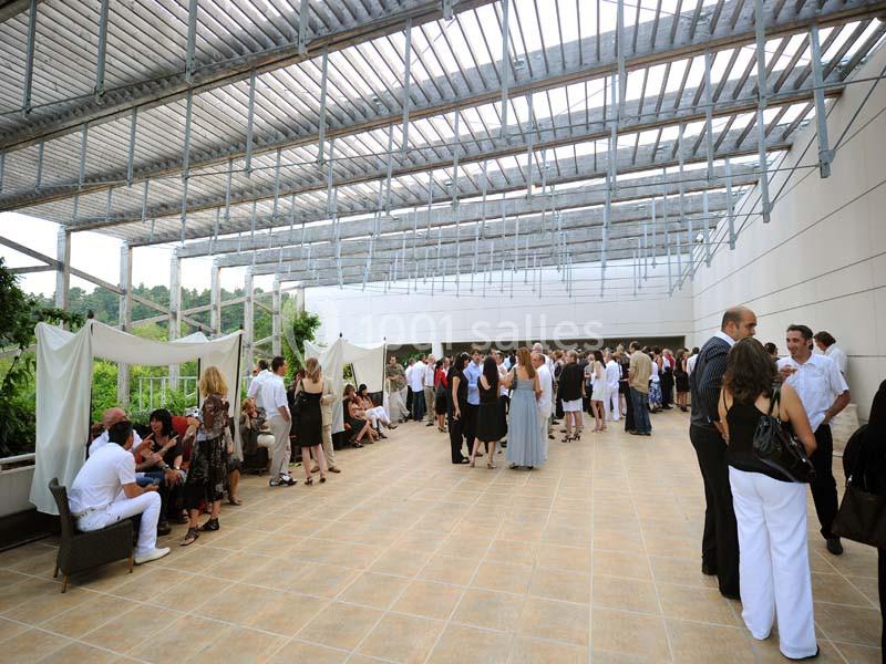 Groupe de personnes rassemblées sur une terrasse couverte, discutant et socialisant lors d'un événement.