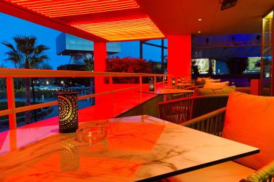 Salle lumineuse avec tables et chaises modernes, sol en moquette, cloison en bois et tapis rouge au centre.