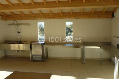 Terrasse extérieure éclairée la nuit, avec des tables et chaises en fer forgé entourées de fleurs colorées.