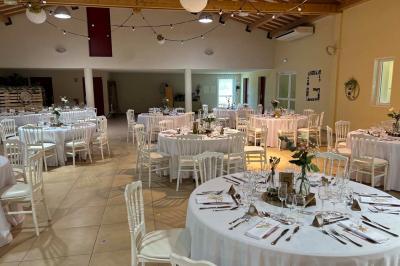 Terrasse extérieure éclairée la nuit, avec des tables et chaises en fer forgé entourées de fleurs colorées.