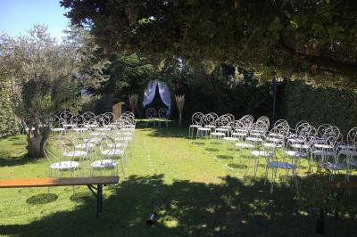Terrasse extérieure éclairée la nuit, avec des tables et chaises en fer forgé entourées de fleurs colorées.